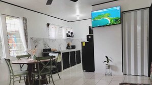 A compact living space with a dining area, kitchenette, and a TV mounted on the wall. - Fully Equipped Kitchen Privacy & Pura Vida (Quepos)