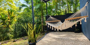 A hammock suspended between two poles in a garden with a variety of plants and a gravel path. - Kitchen • Nature • Privacy & Pura Vida (Quepos)