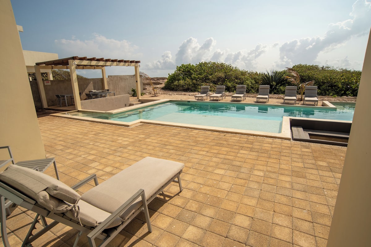 A pool area with lounge chairs and a pergola.