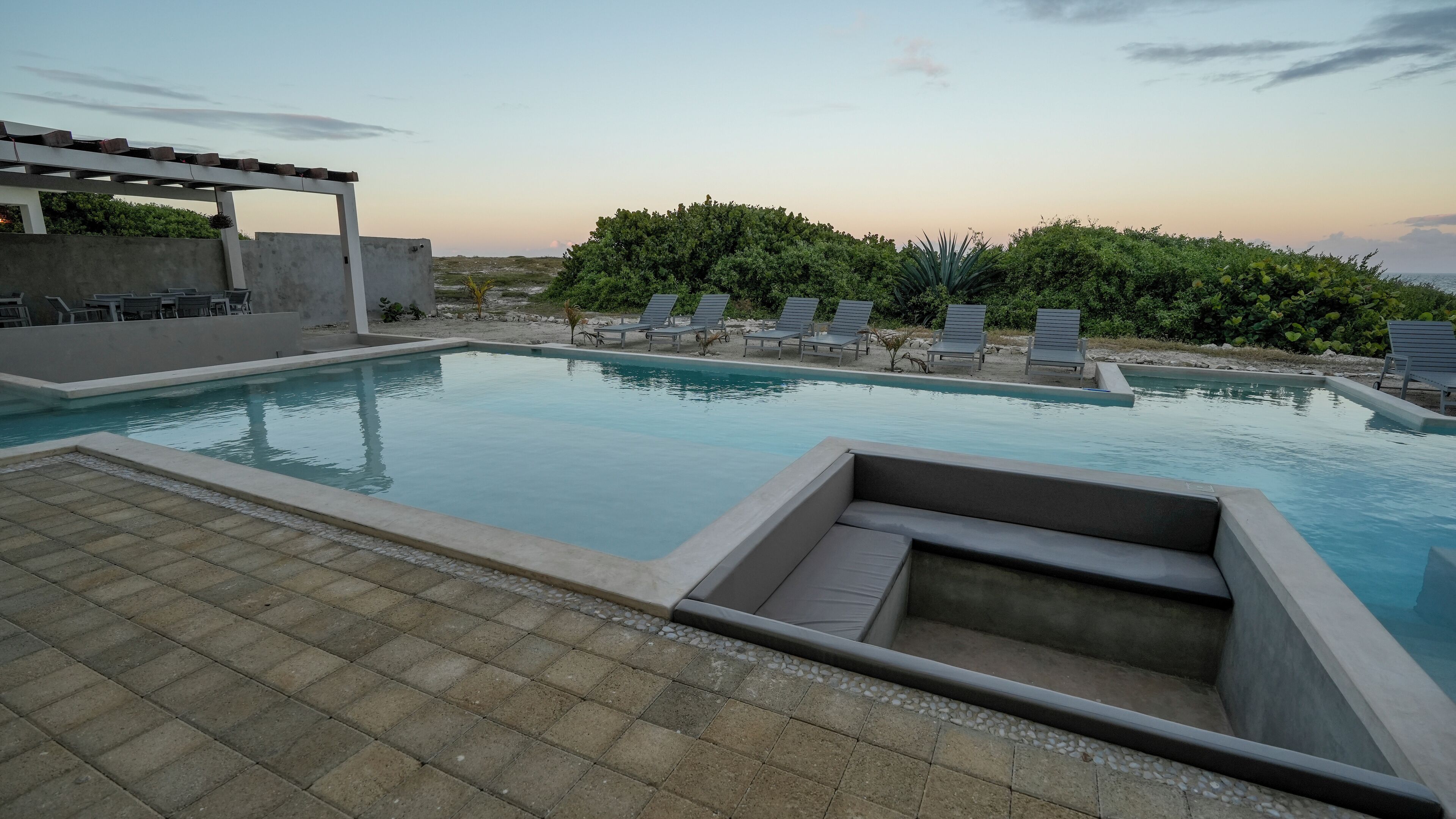 Une piscine avec des chaises longues et une pergola.