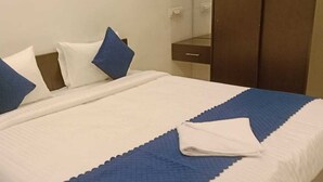 Un lit bien fait, recouvert d’une courtepointe blanche et bleue, avec deux oreillers et une serviette blanche pliée posée sur le côté.