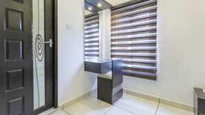 Un couloir moderne avec une porte sombre, un banc intégré et une fenêtre dotée de stores horizontaux.
