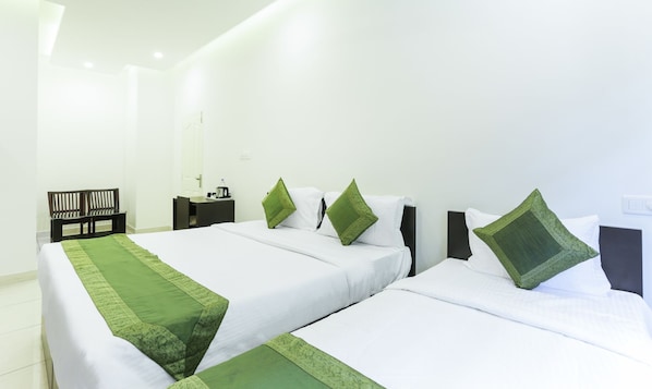Habitación de hotel con dos camas, un escritorio, una silla y una mesita de noche.
