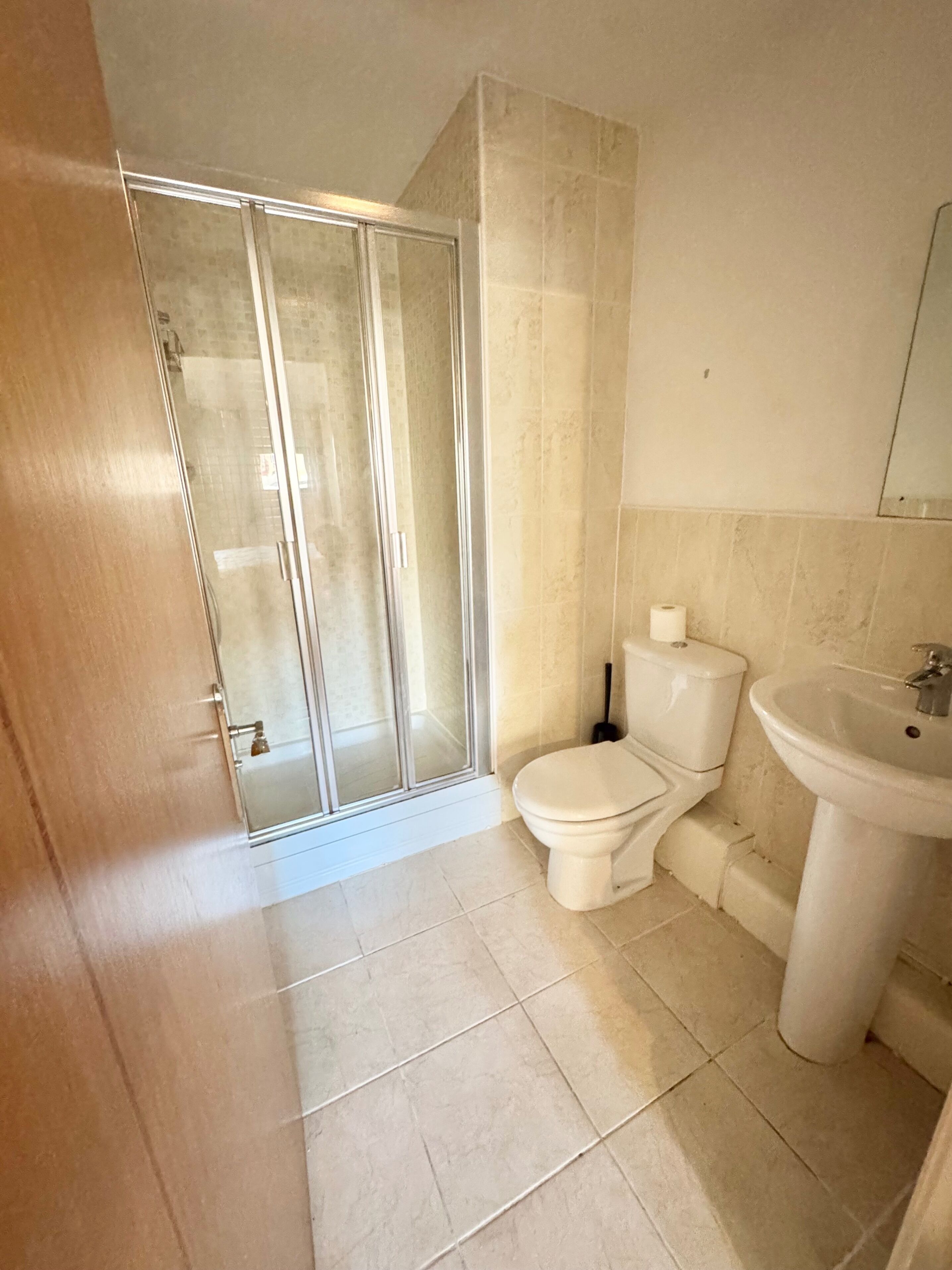 Un baño con cabina de ducha de vidrio, inodoro y lavamanos.