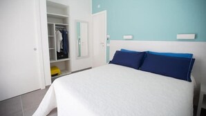 A bedroom with a bed, a wardrobe, and a mirror.