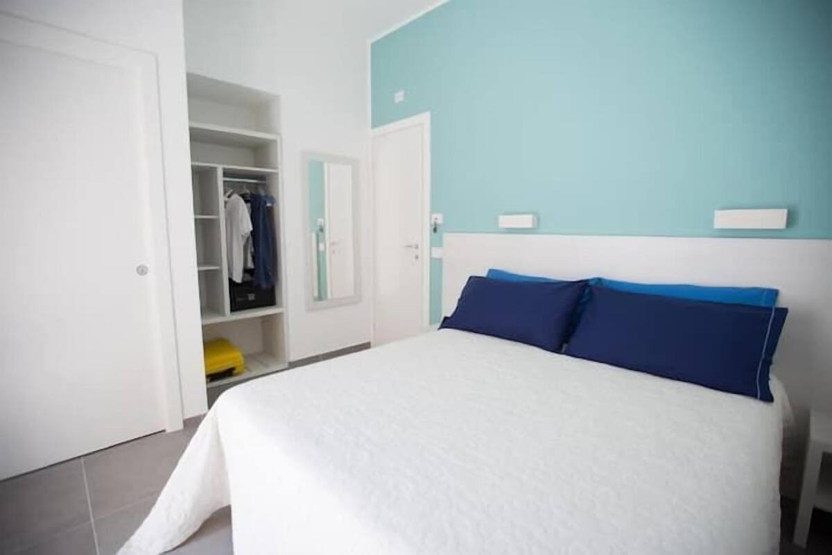 Een slaapkamer met een bed, een kledingkast en een spiegel.