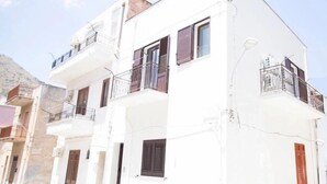 A white three-story building with balconies and wooden shutters.