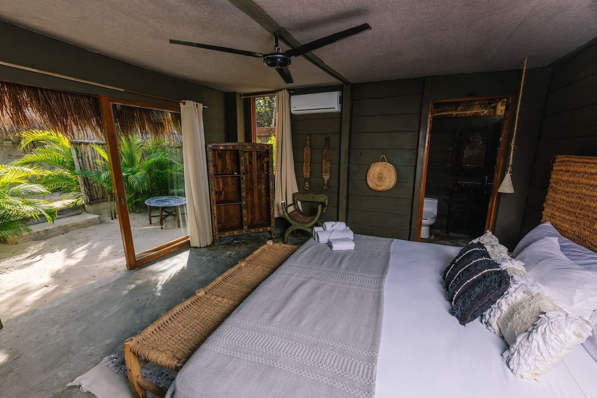 Une chambre à coucher avec un lit, un ventilateur de plafond, une fenêtre et une vue sur l’extérieur.