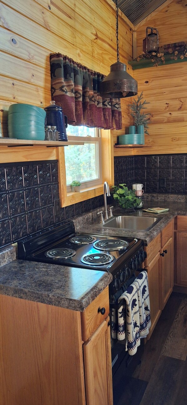 A kitchen with wooden cabinets, a stove, a sink, and a window.