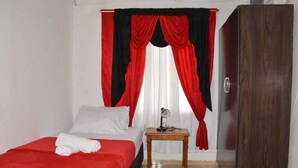 Una habitación de hotel con cama, mesita de noche de madera, espejo y armario.