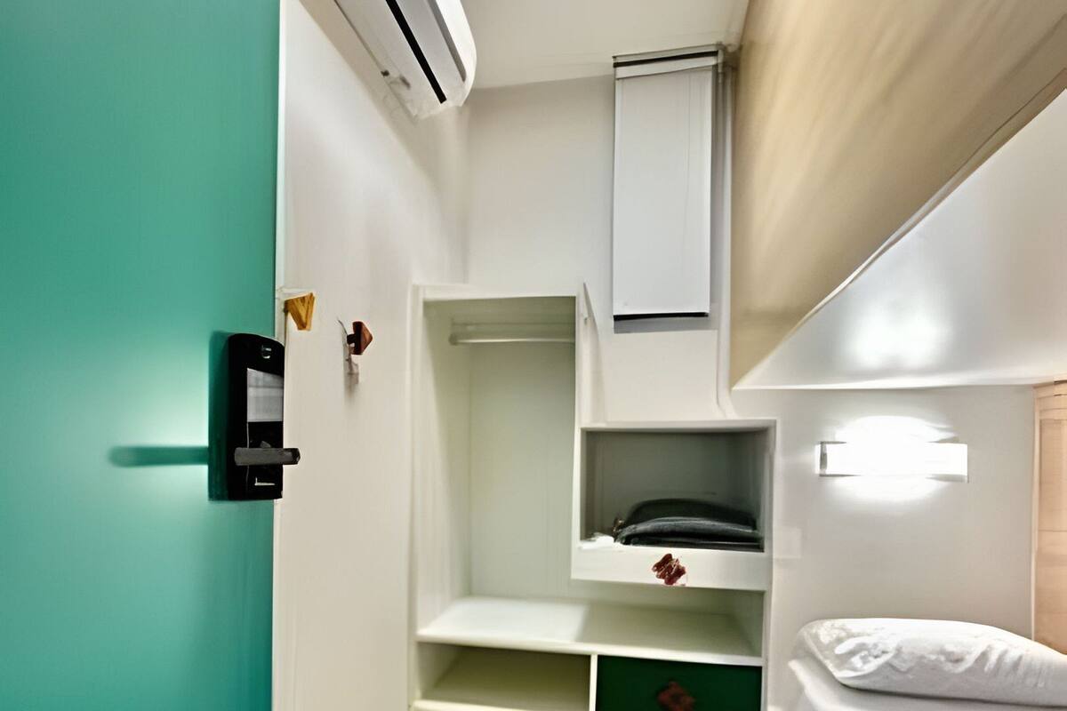 A compact room with a bunk bed, a built-in wardrobe, and a small seating area.