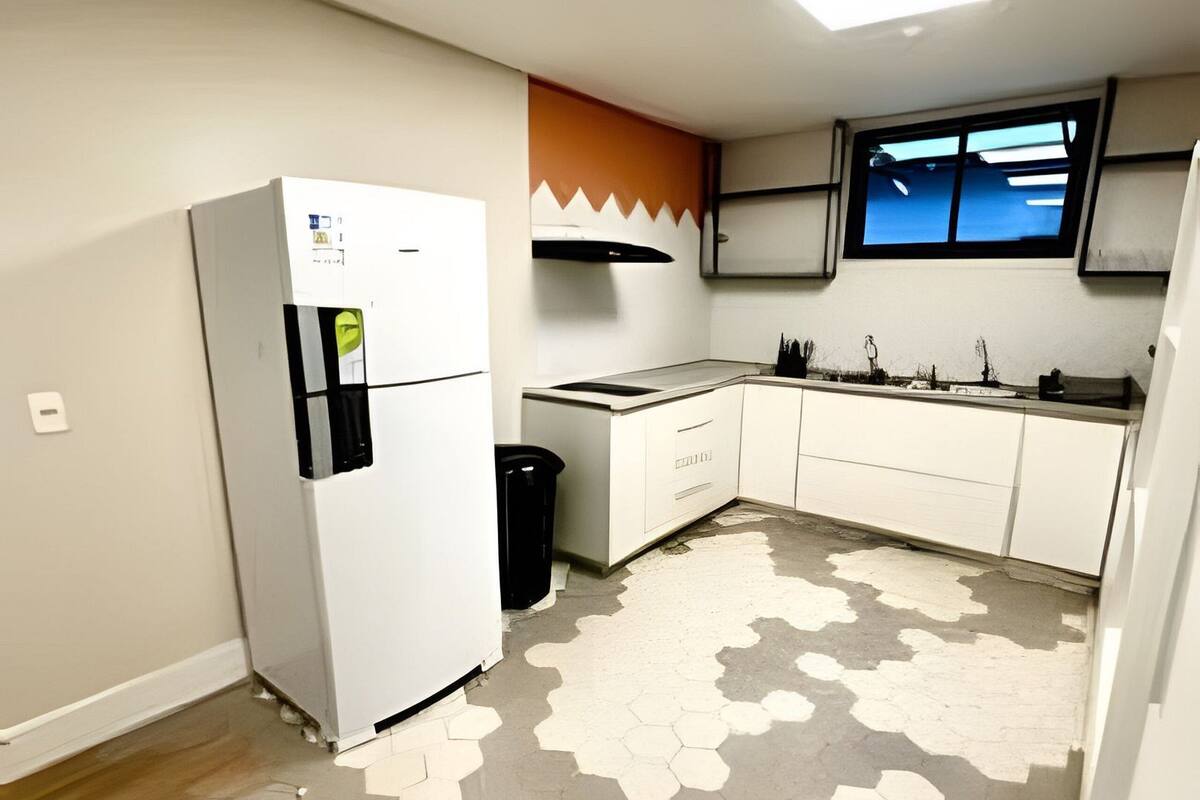 A kitchen with a refrigerator, a sink, and a window.