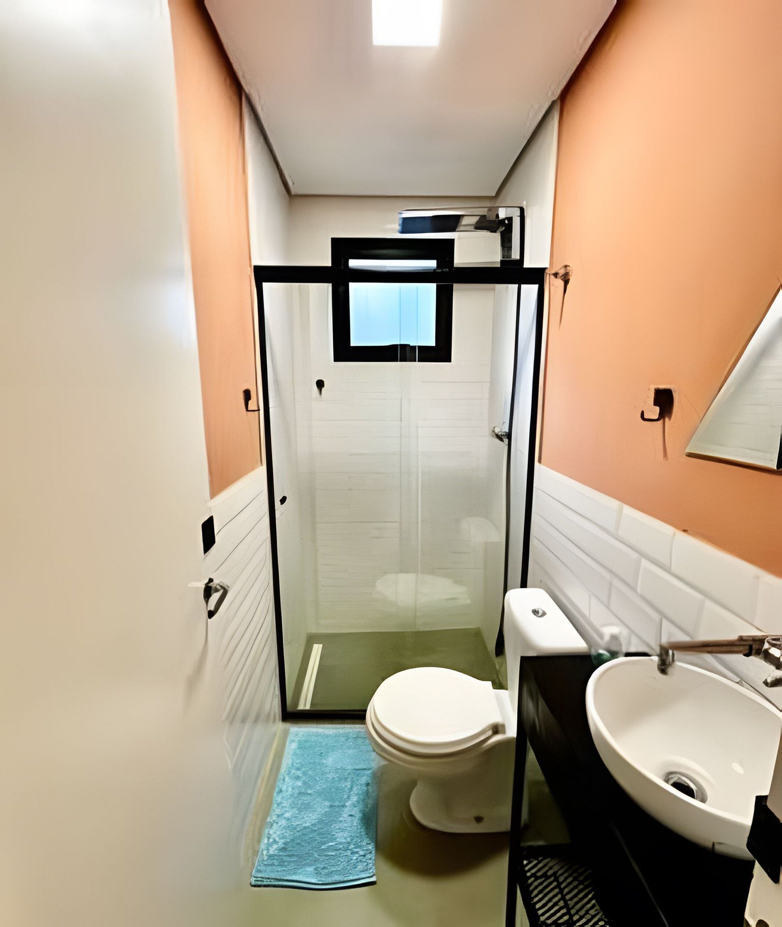 A bathroom with a glass-enclosed shower, a toilet, and a sink.