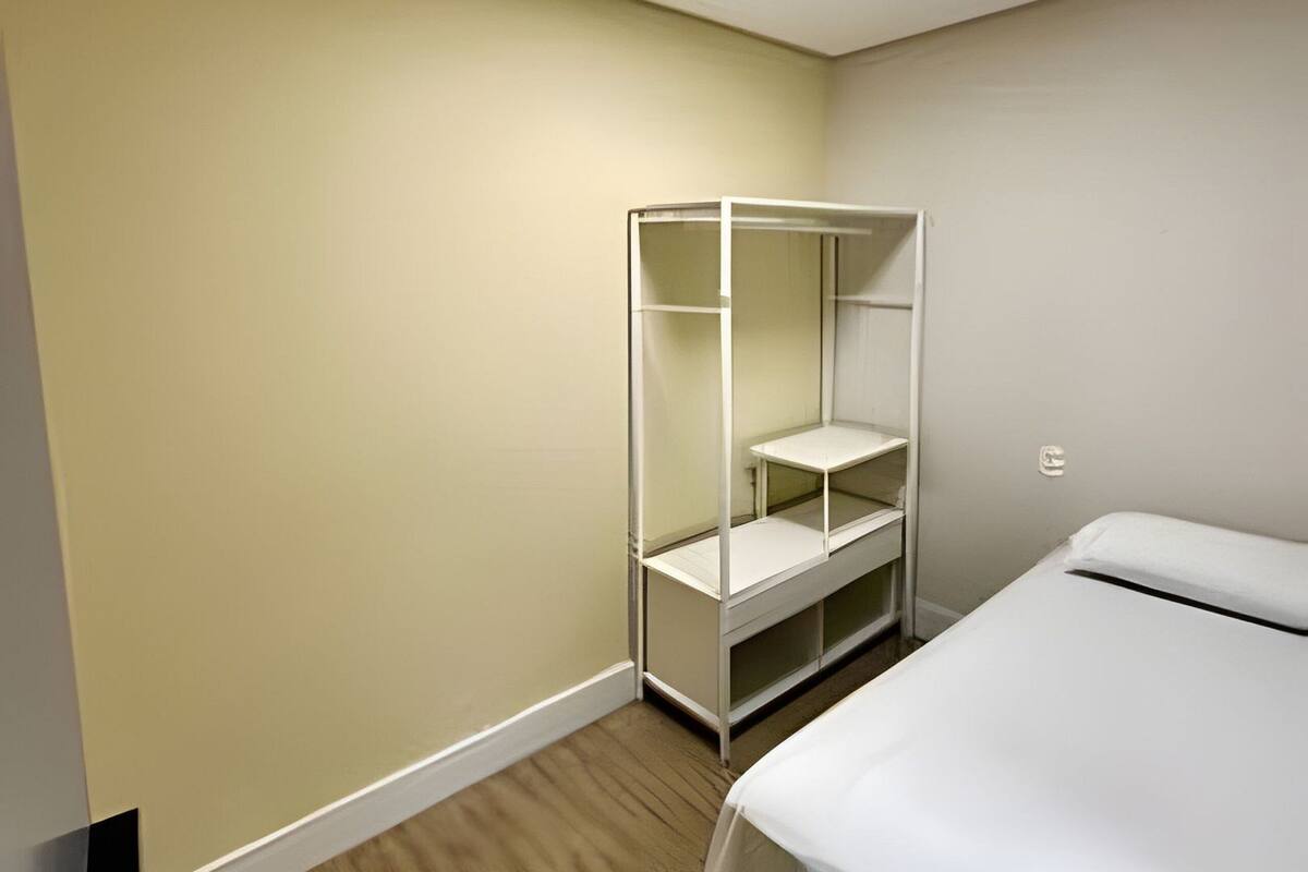 A bedroom with a bed, a white wardrobe, and a ceiling light.