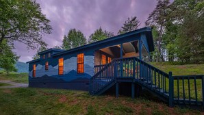 A cabin with a blue exterior, a staircase, and a view of the surrounding landscape. - Blue Ridge Mountains Cabin | Engadine Inn & Cabins (Candler)