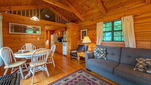 Een gezellig interieur van een chalet, met een eethoek, een bank en een keuken.
