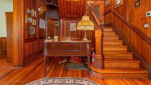 A grand wooden staircase with a lamp and a desk in a richly paneled room. - Vineyard View Suite - Engadine Inn and Cabins (Candler)