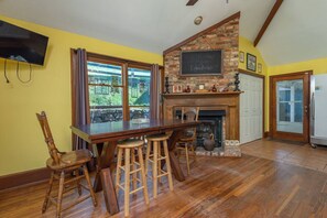 A kitchen with a wooden bar, stone fireplace, and a chalkboard sign. - Vineyard View Suite | Engadine Inn & Cabins (Candler)