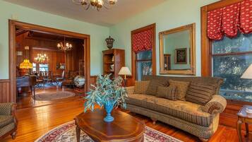 A spacious living room with a wooden floor, a sofa, a coffee table, and a chandelier.