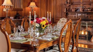 A formal dining room with a wooden table set for six, surrounded by upholstered chairs with floral upholstery. - Brickell Suite - Engadine Inn and Cabins (Candler)
