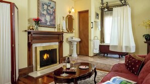 Un salon avec une cheminée, un canapé, une table basse avec des boissons et un tableau accroché au mur.