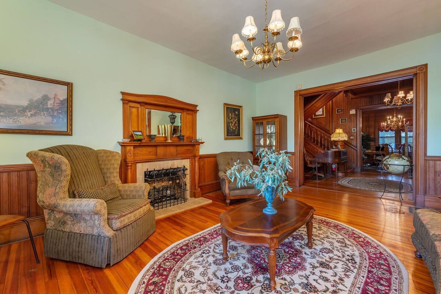 A spacious living room with a fireplace, wooden furniture, and a chandelier.