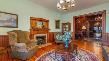 A spacious living room with a fireplace, wooden furniture, and a chandelier.