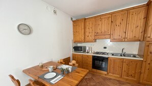 Uma cozinha compacta com armários de madeira, micro-ondas, fogão e máquina de lavar louça.
