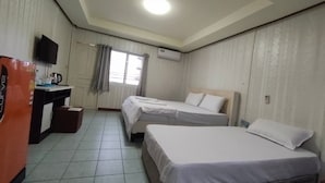 Een hotelkamer met twee eenpersoonsbedden, een klein bureau met stoel, een televisie en een raam met gordijnen.