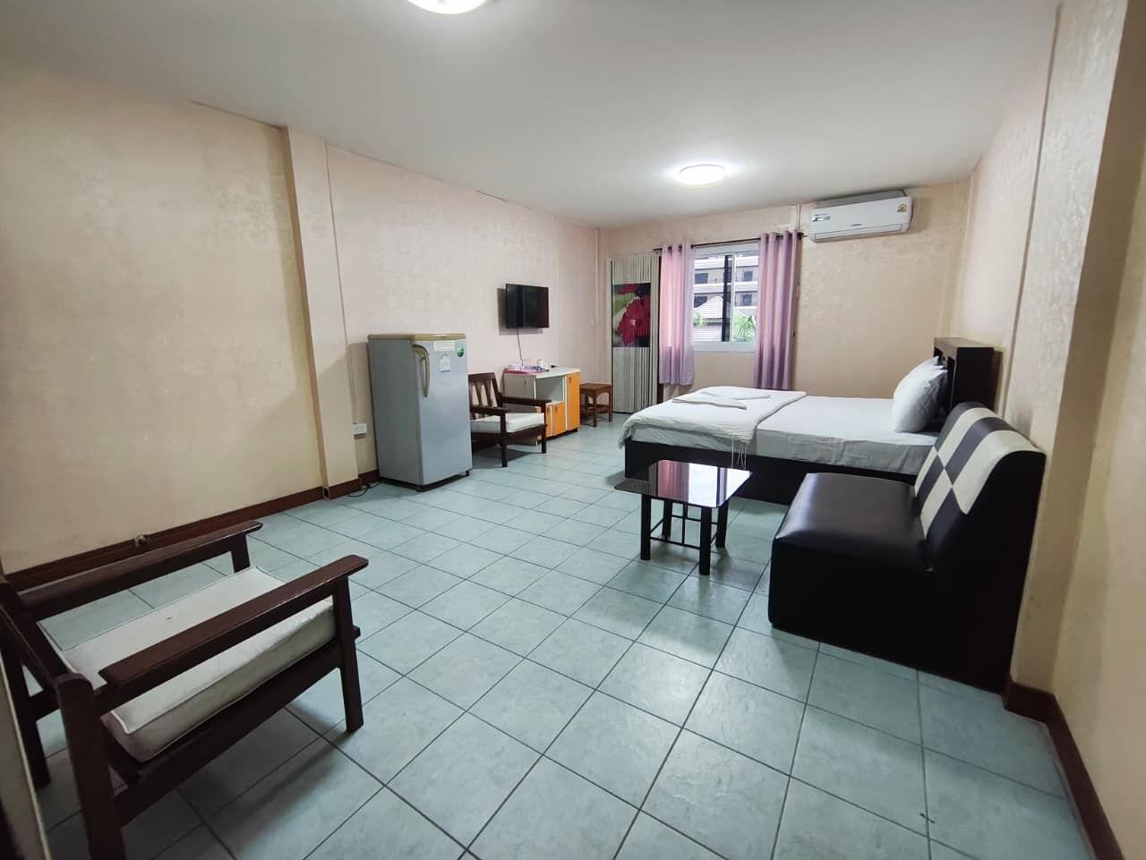 A small, clean room with a bed, a sofa, a desk, and a chair.