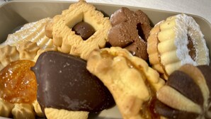 Un plateau contenant un assortiment de pâtisseries, notamment des biscuits, une confiserie enrobée de chocolat et une tarte saupoudrée de sucre glace.
