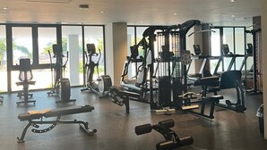 Un gimnasio moderno con diferentes equipos de ejercicio, amplias ventanas y un diseño limpio y espacioso.
