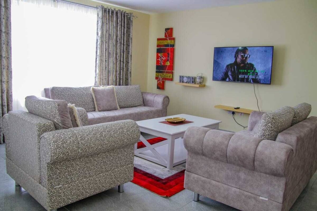 Un salon avec deux canapés, une table basse et un téléviseur fixé au mur.