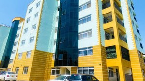 Un immeuble à plusieurs étages, doté d’une façade jaune et bleue, agrémentée de balcons et de grandes fenêtres.
