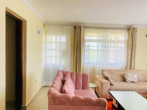 Una sala de estar con un sofá rosa, un sofá color beige y una mesita.