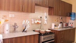 Une cuisine moderne dotée de meubles en bois, d’une cuisinière à gaz, d’un four à micro-ondes et de divers ustensiles de cuisine.