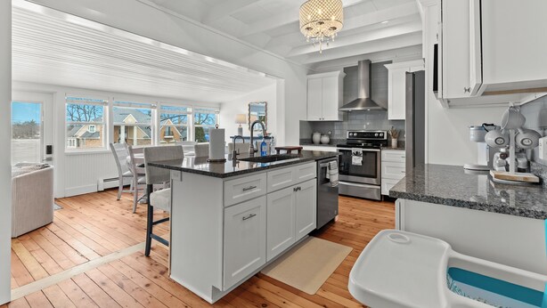 Una cocina moderna con armarios blancos, una isla central y un amplio ventanal con vista al vecindario.