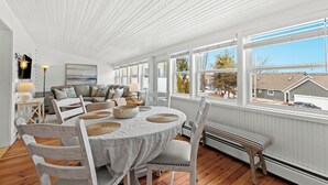 Un salón luminoso y espacioso con comedor, ventanas grandes y vistas al barrio.