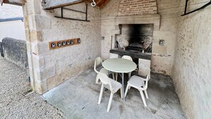 An outdoor patio with a brick oven, a round table, and four chairs. - Charming 3 bedroom house (Lussac-les-Châteaux)