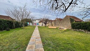 A stone pathway leading to a building with a tiled roof, surrounded by greenery and a mural. - Charming 3 bedroom house (Lussac-les-Châteaux)