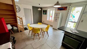 Una cocina moderna con una mesa redonda, sillas amarillas, un refrigerador y una ventana con vista a follaje.