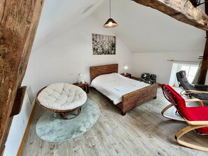 A bedroom with a large bed, a round chair, a rocking chair, and a hanging light fixture. - Bedroom is a cosy house (Lussac-les-Châteaux)