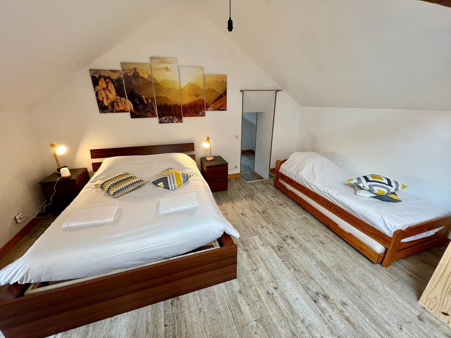 Un dormitorio con dos camas, piso de madera y un cuadro en la pared.