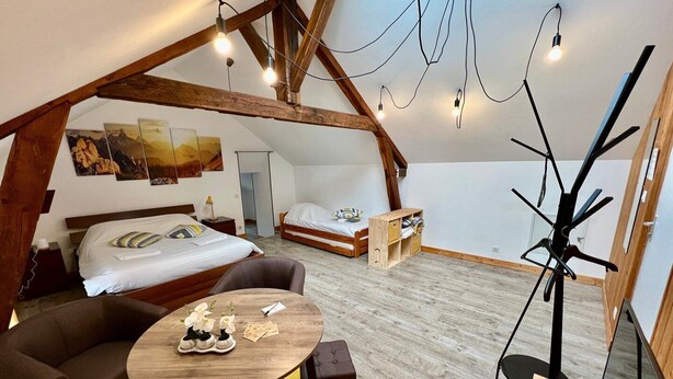 Een knus loft slaapkamer met een groot bed, een bureau, een stoel en een klein tafeltje met bloemen.