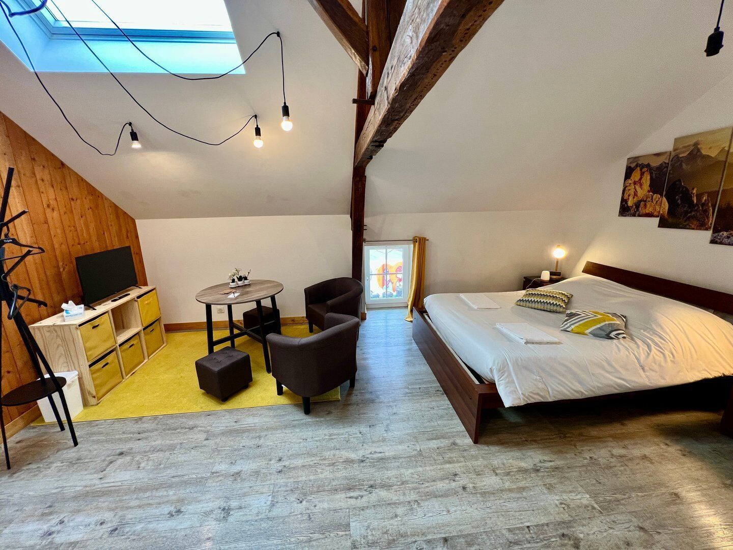 Un dormitorio acogedor en el ático, con cama, una mesita y un televisor.