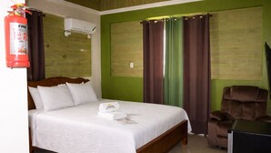 Habitación de hotel con cama, una silla, un extintor y un equipo de aire acondicionado.