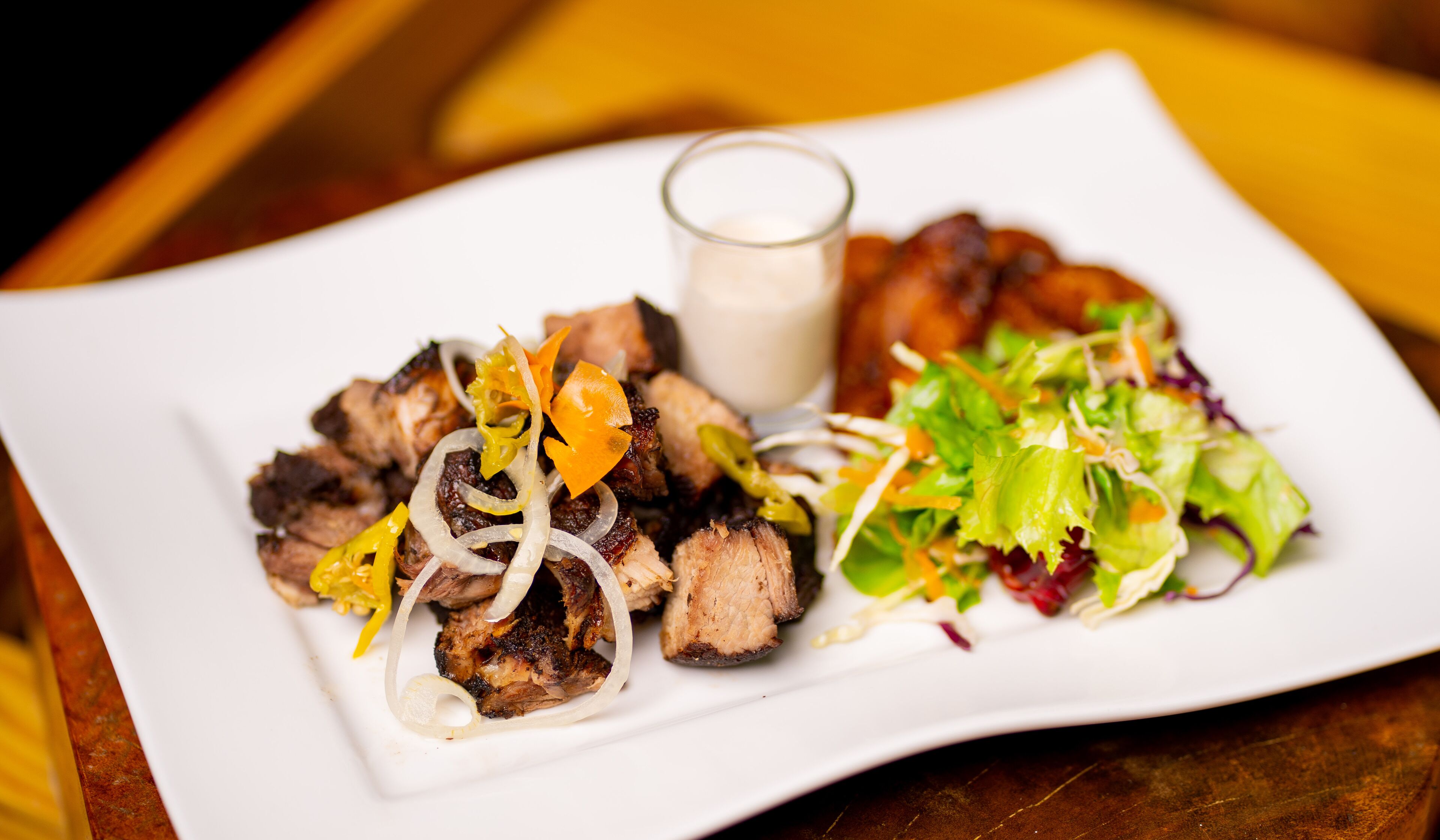 A plate of food with grilled meat, onions, and a salad.