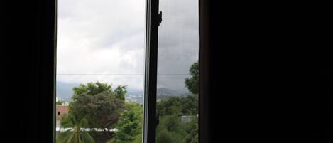 A window with a view of a red-roofed building and trees.