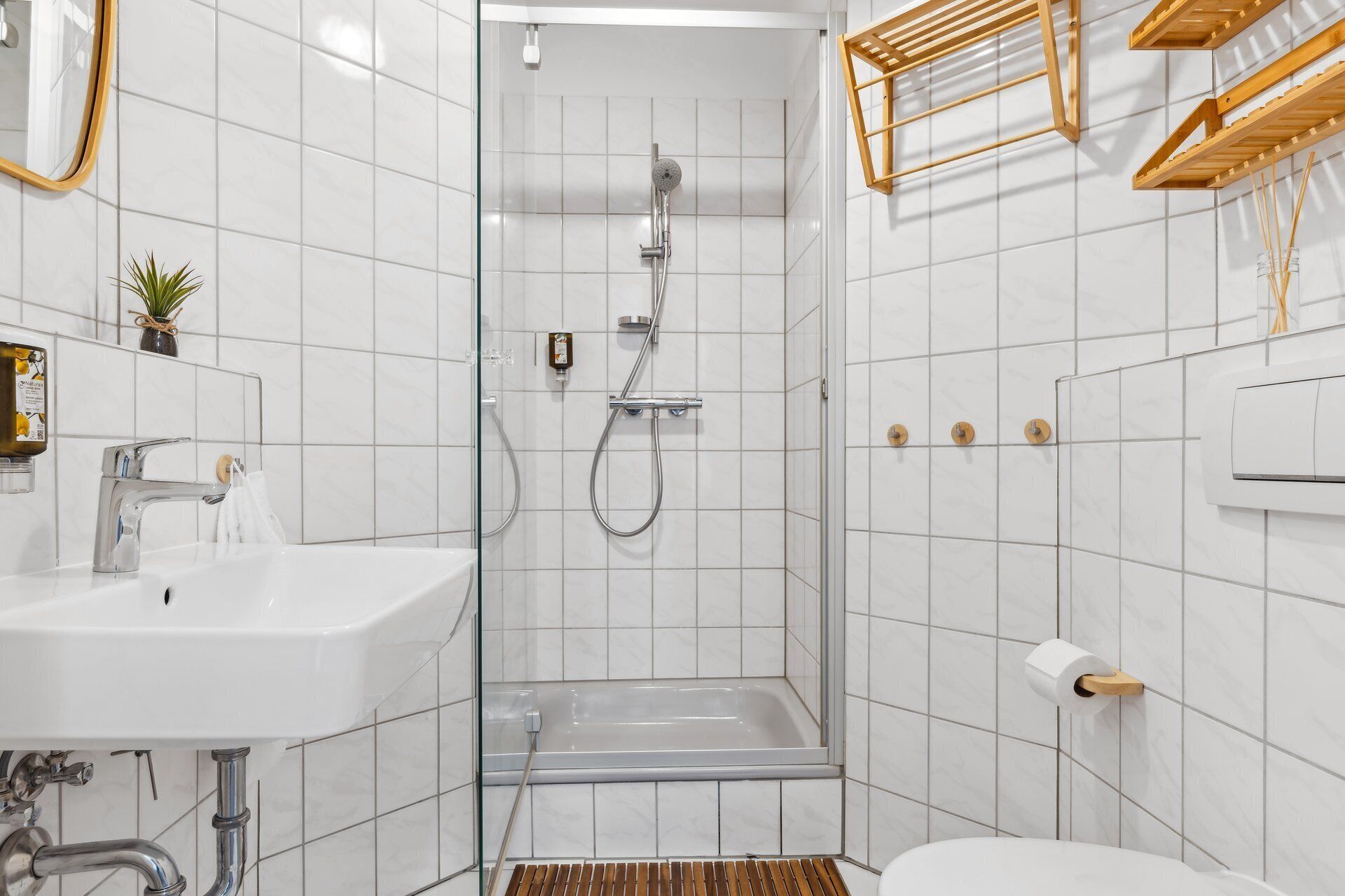 Ein modernes Badezimmer mit einer Duschkabine, einem weißen Waschbecken und einer Toilette.