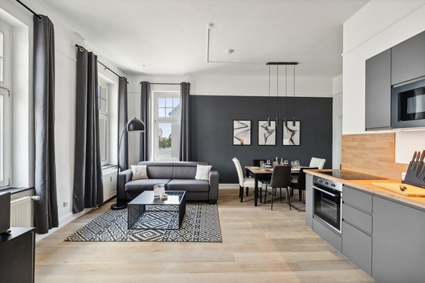 Großes, stilvolles Wohnzimmer mit Smart-TV, Schlafcouch, Essbereich & Küche.